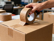 Papier-Packband mit Handabroller beim Verschließen eines Versandkartons im Lager